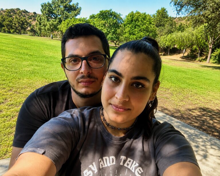 The two founders of Kore Studio smiling in a park with very green trees in the background.